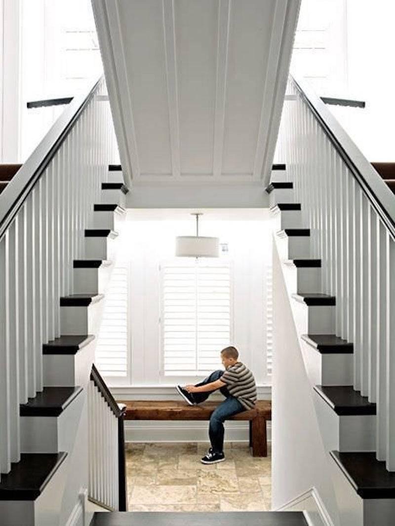 kid tying shoes in room under stairs